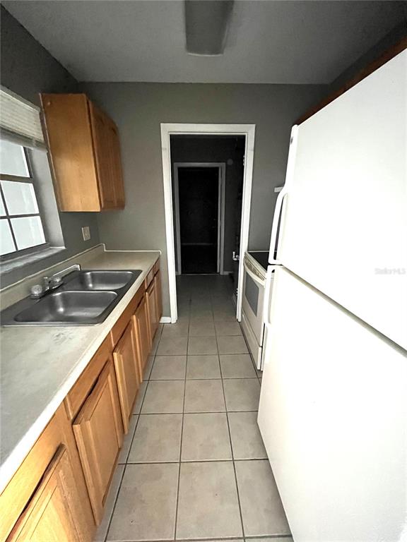 A galley-style kitchen features light wood cabinets, a double sink, and a white refrigerator — 2603 SW 152ND LANE, OCALA, FL
