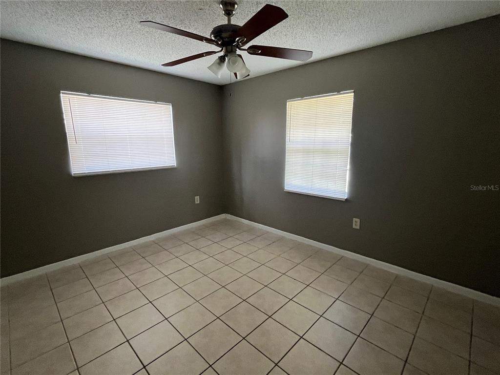 An empty bedroom features gray walls, tile flooring, and a ceiling fan — 2603 SW 152ND LANE, OCALA, FL