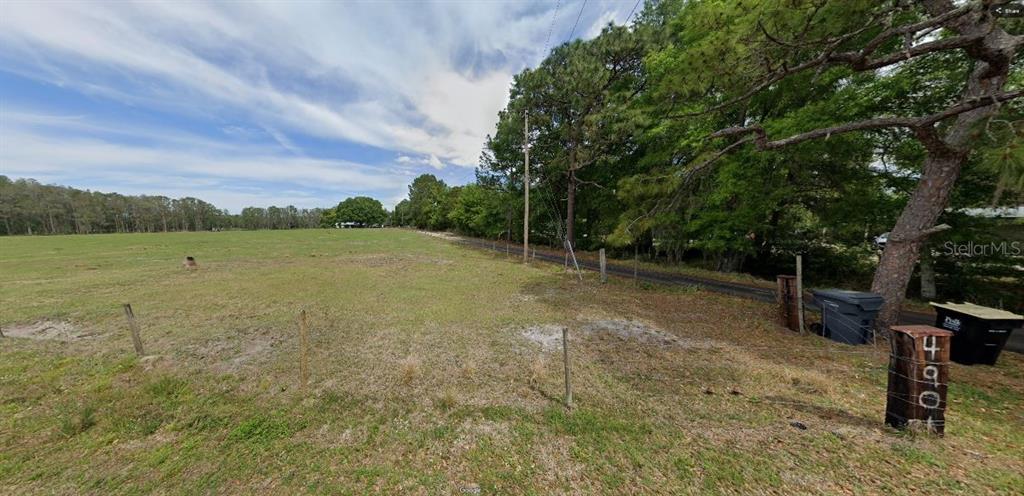 A grassy, fenced-in vacant lot features a wooden post with the number 460 — GREEN POND RD, POLK CITY, FL