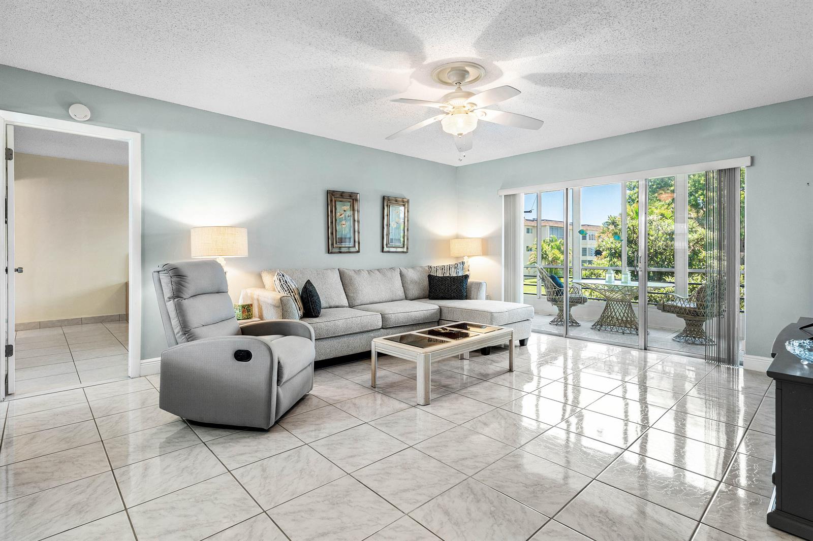 A living room features light blue walls, a gray sectional, a recliner, and tiled floors — 721 Lori Drive # 208, Palm Springs FL 33461, PALM SPRINGS, FL