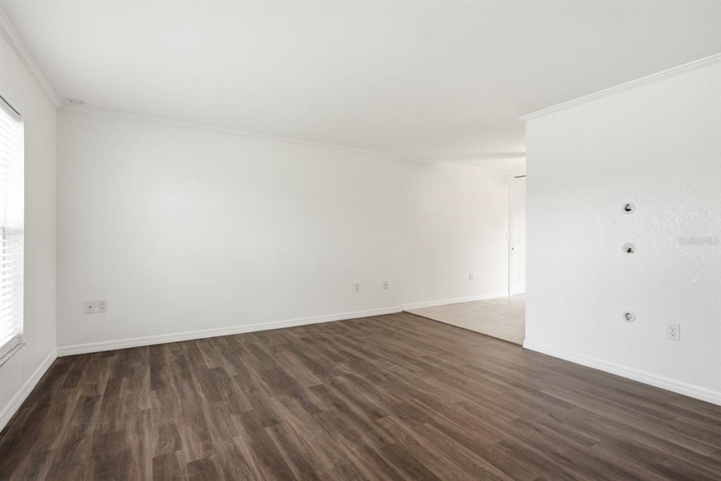 An empty room with white walls, wood-look flooring, and a doorway leading to another area — 7826 KNOX LOOP, NEW PORT RICHEY, FL