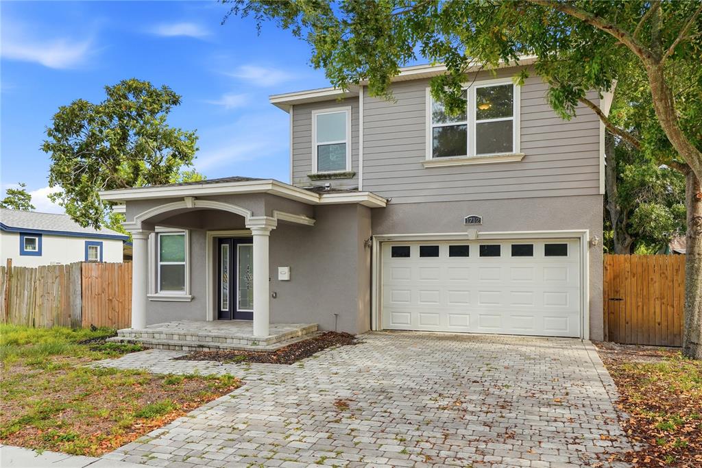 A two-story house with gray siding, a paved driveway, and a covered front porch — 1712 31ST AVENUE N, ST PETERSBURG, FL