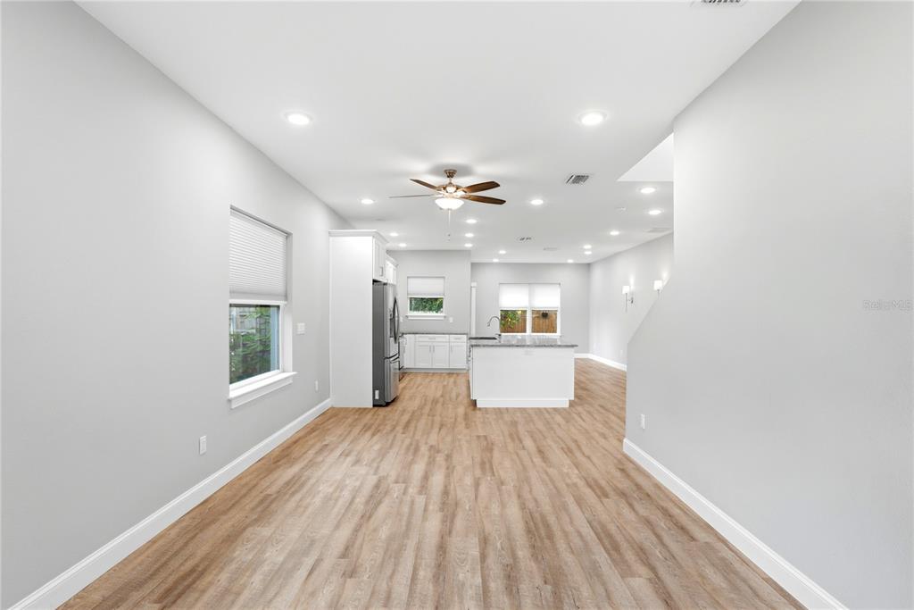 An open-concept kitchen and living area features light wood flooring, white cabinetry, and recessed lighting — 1712 31ST AVENUE N, ST PETERSBURG, FL