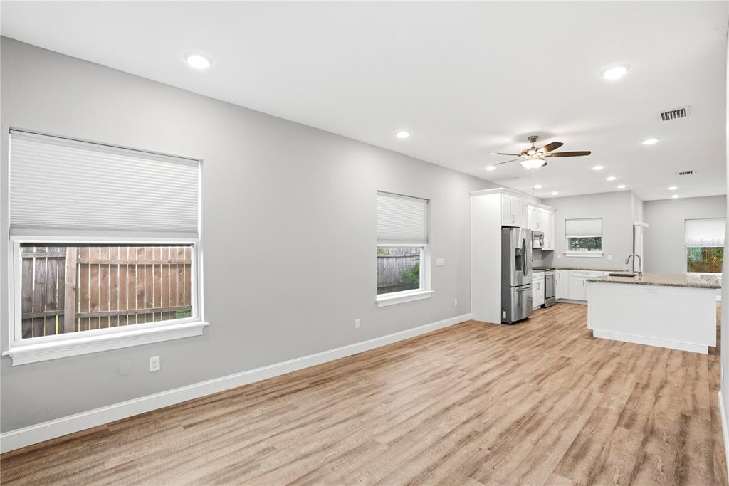 An open-concept kitchen and living area features light gray walls, wood-look flooring, and white cabinetry — 1712 31ST AVENUE N, ST PETERSBURG, FL