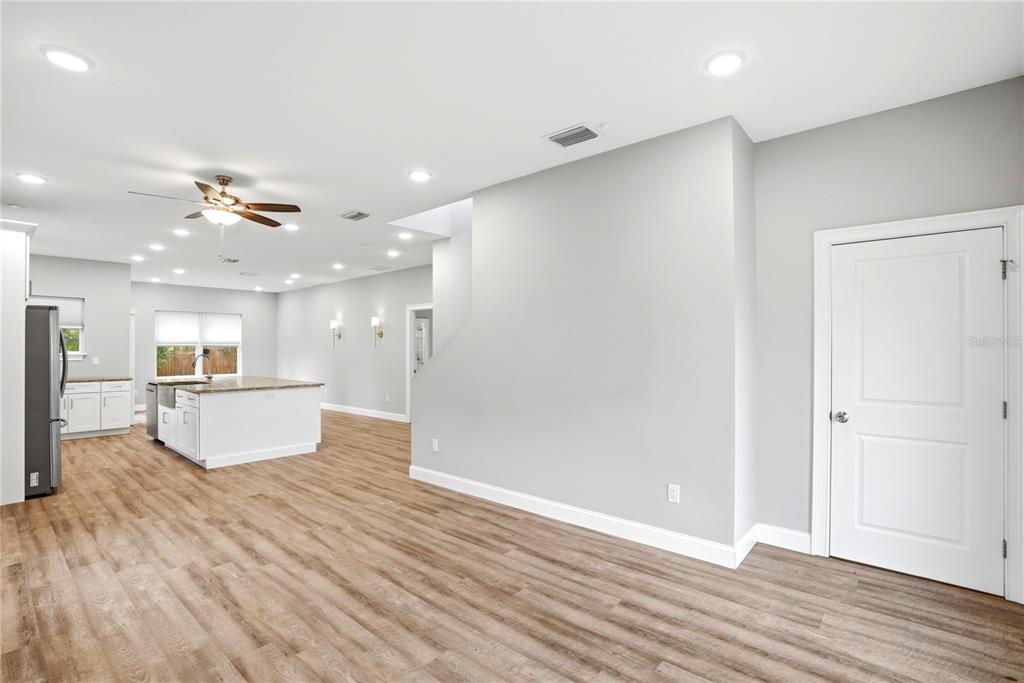 A bright, open-concept kitchen and living area featuring light wood flooring and white cabinetry — 1712 31ST AVENUE N, ST PETERSBURG, FL