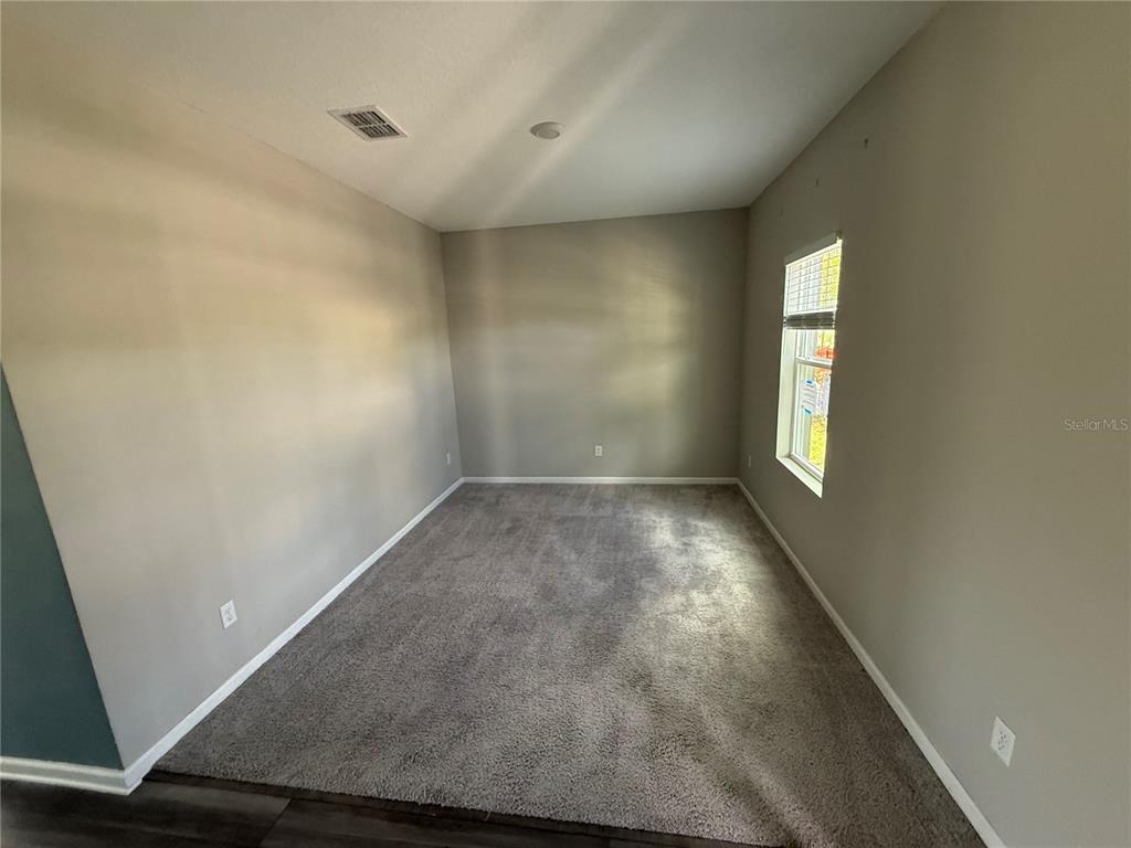 An empty room features gray walls, neutral carpeting, and a single window on the right — 462 SPOTTED SLIPPER PLACE, RUSKIN, FL