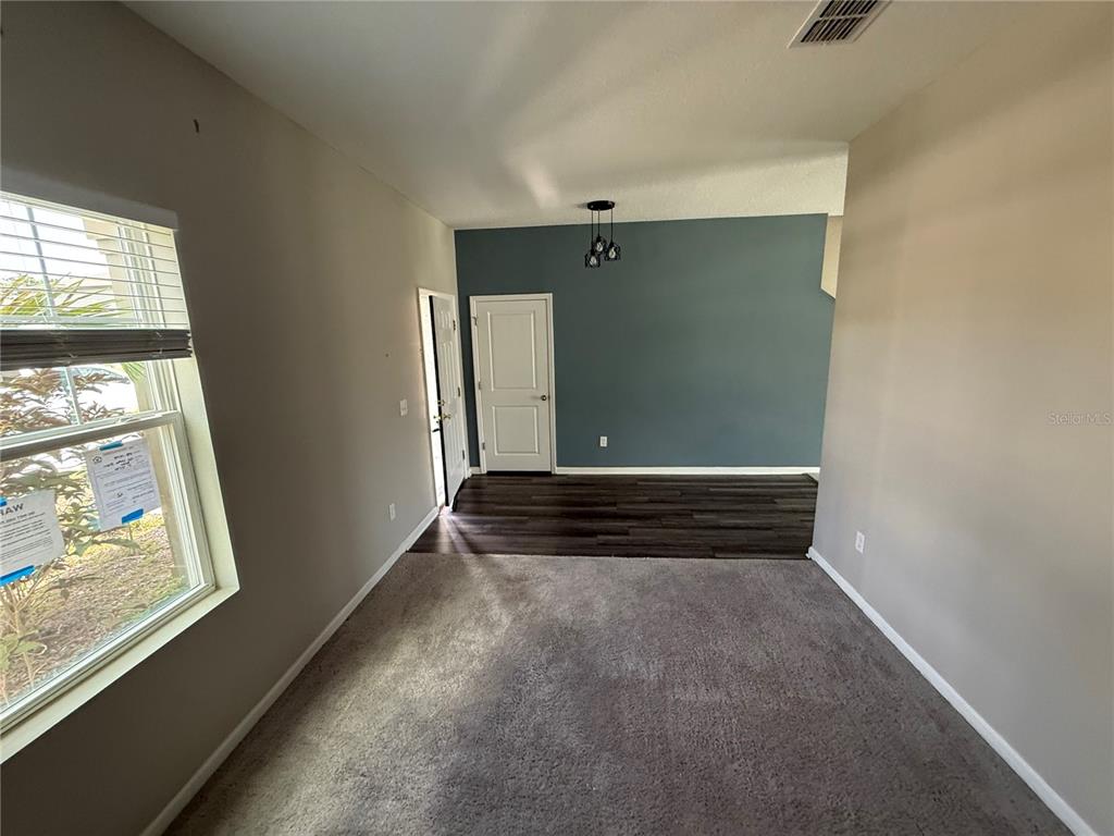 A room features gray carpet, a dark wood-floored entryway, and a blue accent wall — 462 SPOTTED SLIPPER PLACE, RUSKIN, FL
