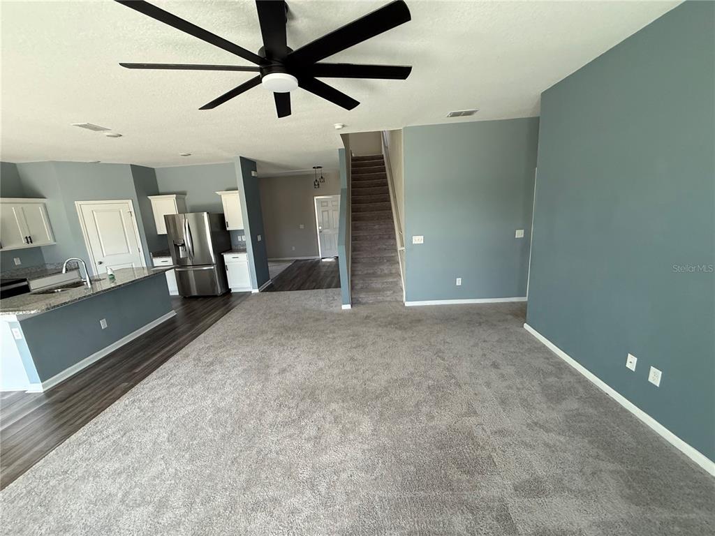 A living room with gray carpet, a ceiling fan, and stairs leading to an upper level — 462 SPOTTED SLIPPER PLACE, RUSKIN, FL