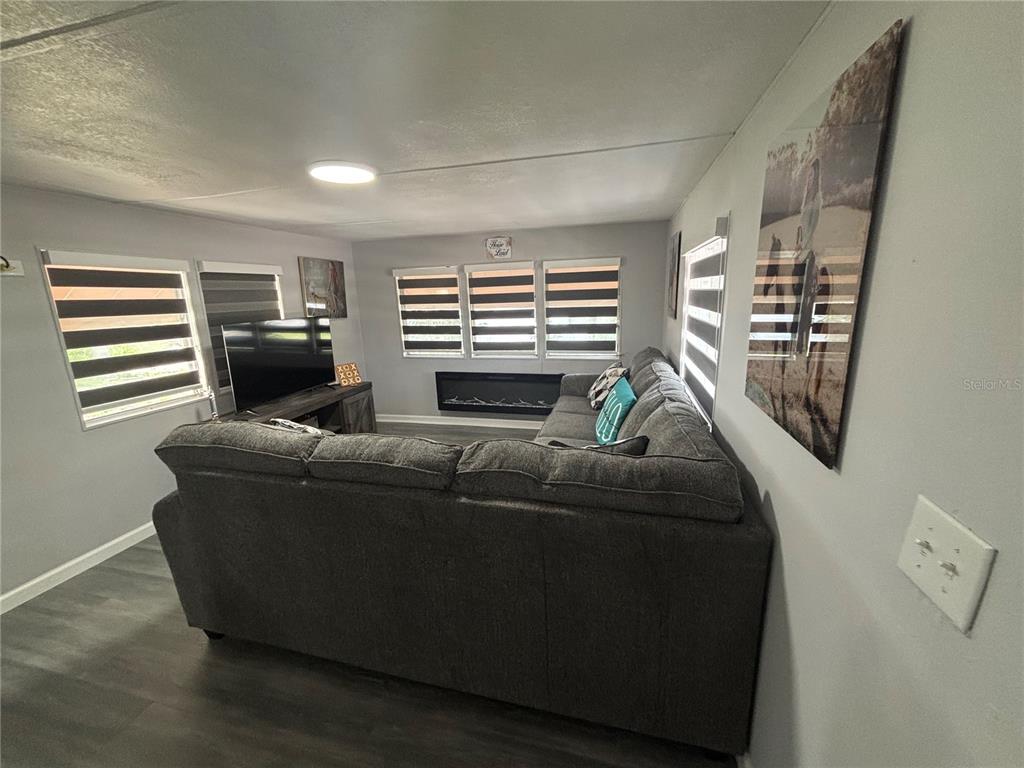 A living room features gray flooring, a large sectional sofa, a television, and a fireplace — 6141 SW 57TH COURT, OCALA, FL