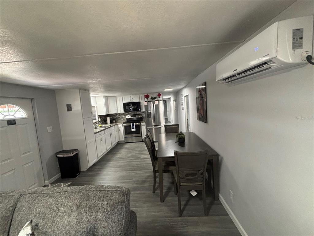 An open-concept kitchen and dining area with gray wood-look flooring and a wall-mounted air conditioner — 6141 SW 57TH COURT, OCALA, FL