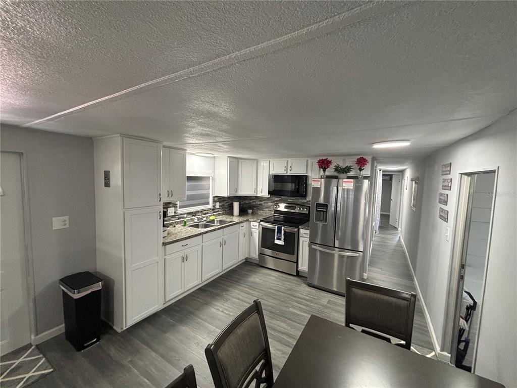 A kitchen with white cabinets, stainless steel appliances, and gray wood-look flooring — 6141 SW 57TH COURT, OCALA, FL
