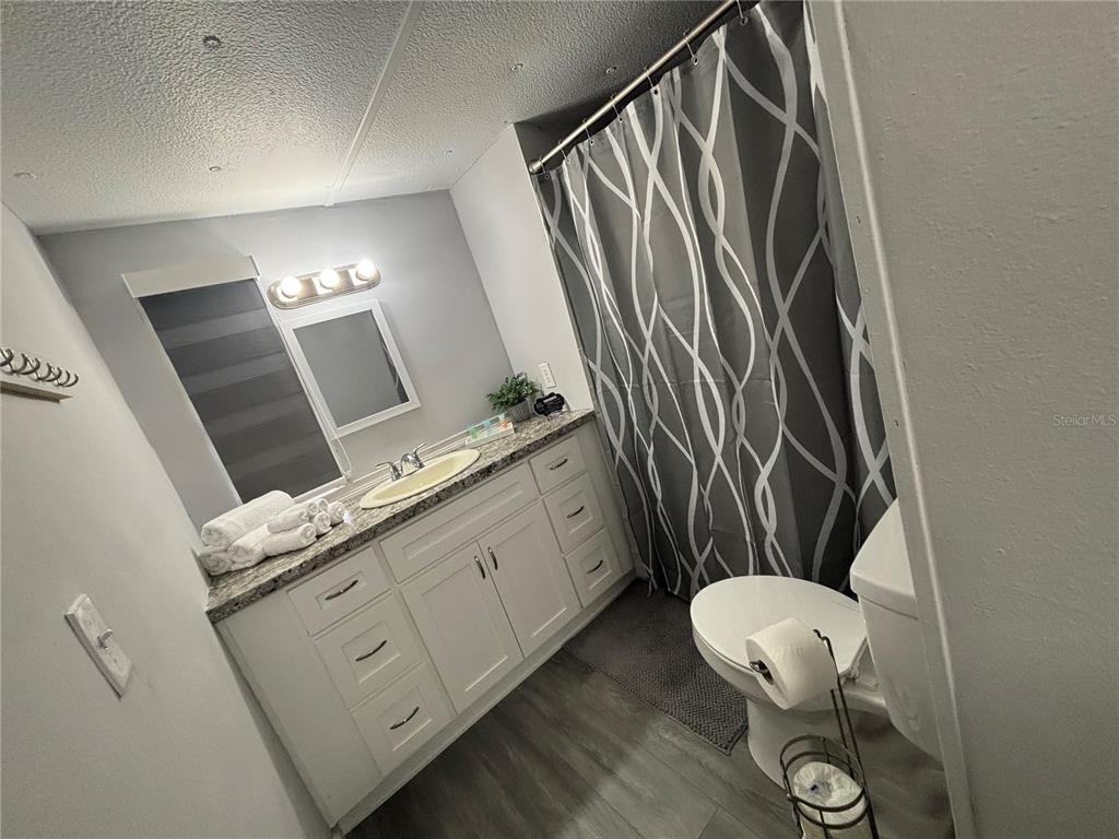 A bathroom features a white vanity with a granite countertop, a mirror, and a shower curtain — 6141 SW 57TH COURT, OCALA, FL