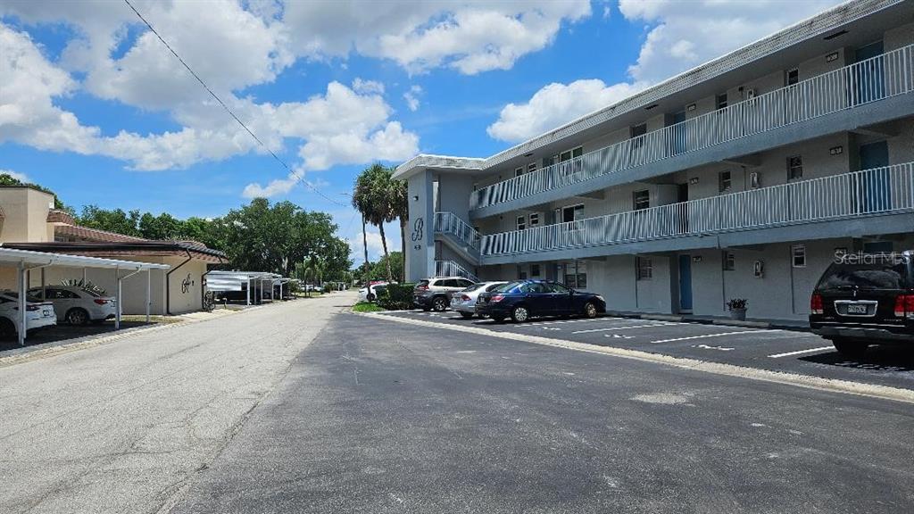 A three-story apartment building with exterior walkways and a parking lot in front — 9950 47TH AVENUE N UNIT 303, ST PETERSBURG, FL