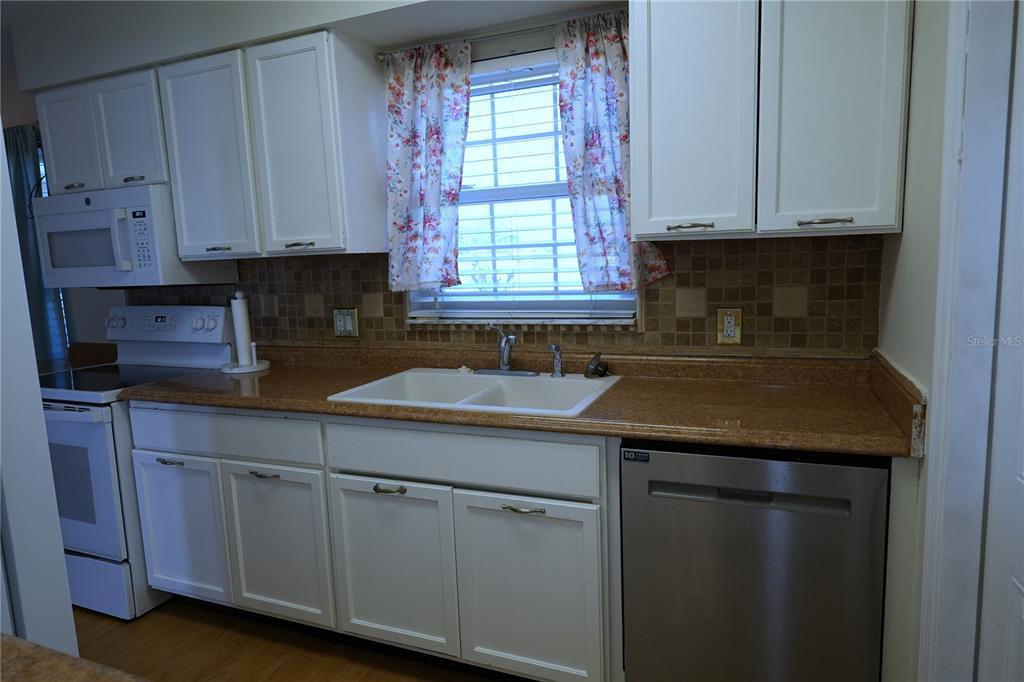 A kitchen features white cabinets, a stainless steel dishwasher, and a tan countertop — 3074 PERDUE TERRACE, PUNTA GORDA, FL
