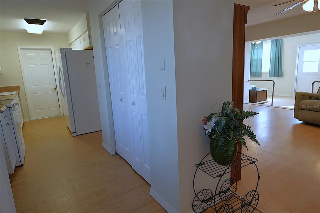 A view of a kitchen with light wood flooring, white cabinets, and a living area — 3074 PERDUE TERRACE, PUNTA GORDA, FL
