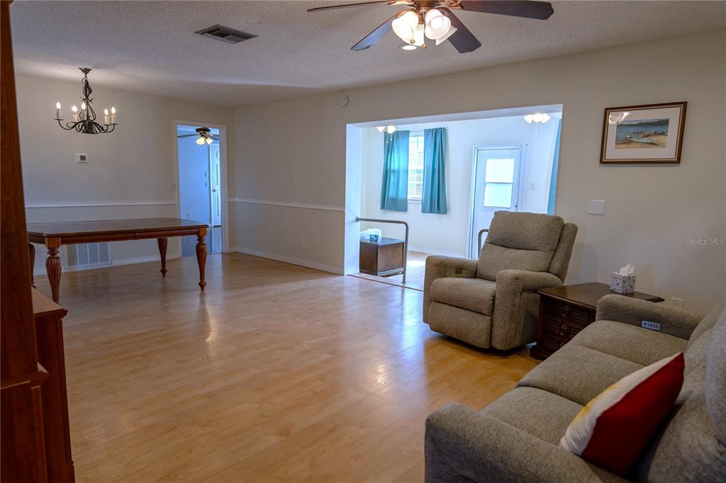 A living room with light wood flooring, a recliner, a sofa, and a dining area — 3074 PERDUE TERRACE, PUNTA GORDA, FL