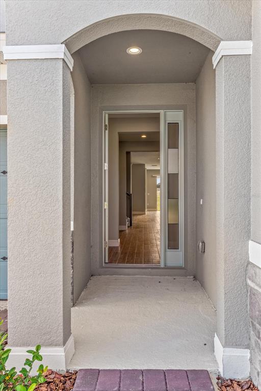 A front entryway with a recessed porch, a glass-paneled door, and a view into the home — 17314 WILD DAISY DRIVE, WINTER GARDEN, FL