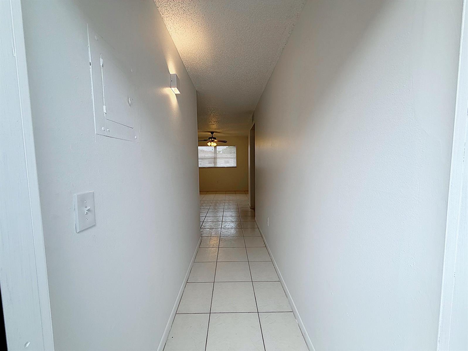 A narrow hallway with white walls and light-colored square floor tiles leads to a room — 650 SW 2nd SW # 2480, Boca Raton FL 33432, BOCA RATON, FL