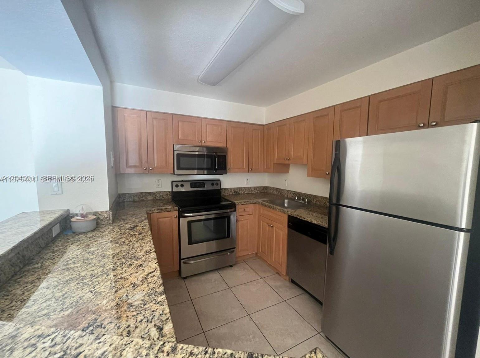 A kitchen features light wood cabinets, granite countertops, and stainless steel appliances — 5112 NW 79 Ave # 202, Doral FL 33166, DORAL, FL