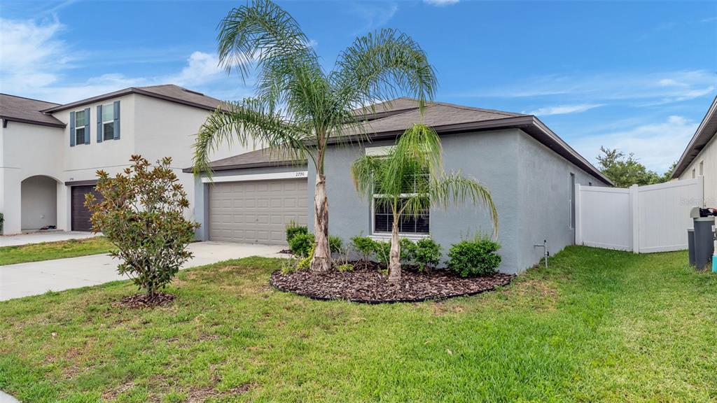 A single-story house with a gray stucco exterior, a two-car garage, and a palm tree — 2790 RED EGRET DRIVE, BARTOW, FL