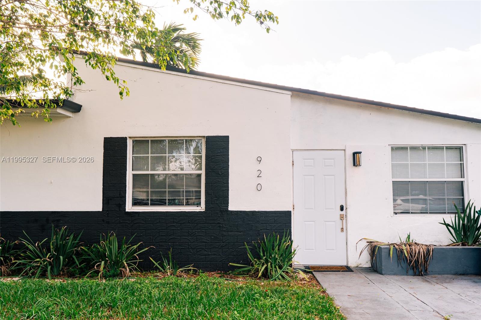 The exterior of a white house features black painted brick accents and a white door — 920 NW 84th St, Miami FL 33150, MIAMI, FL