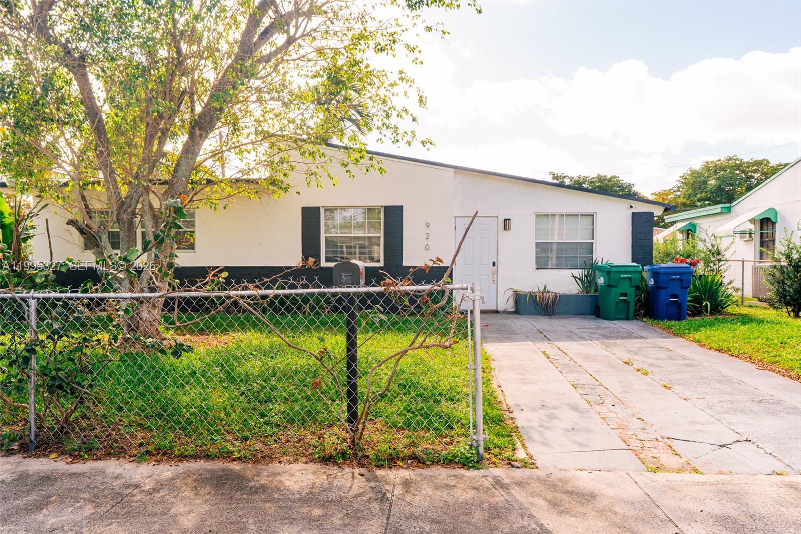 A single-story house with a white exterior, black shutters, and a chain-link fence — 920 NW 84th St, Miami FL 33150, MIAMI, FL