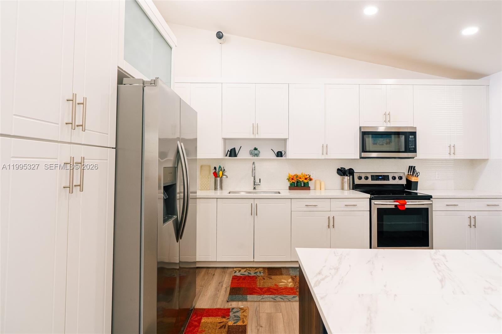 A modern kitchen features white cabinetry, stainless steel appliances, and a marble-topped island — 920 NW 84th St, Miami FL 33150, MIAMI, FL