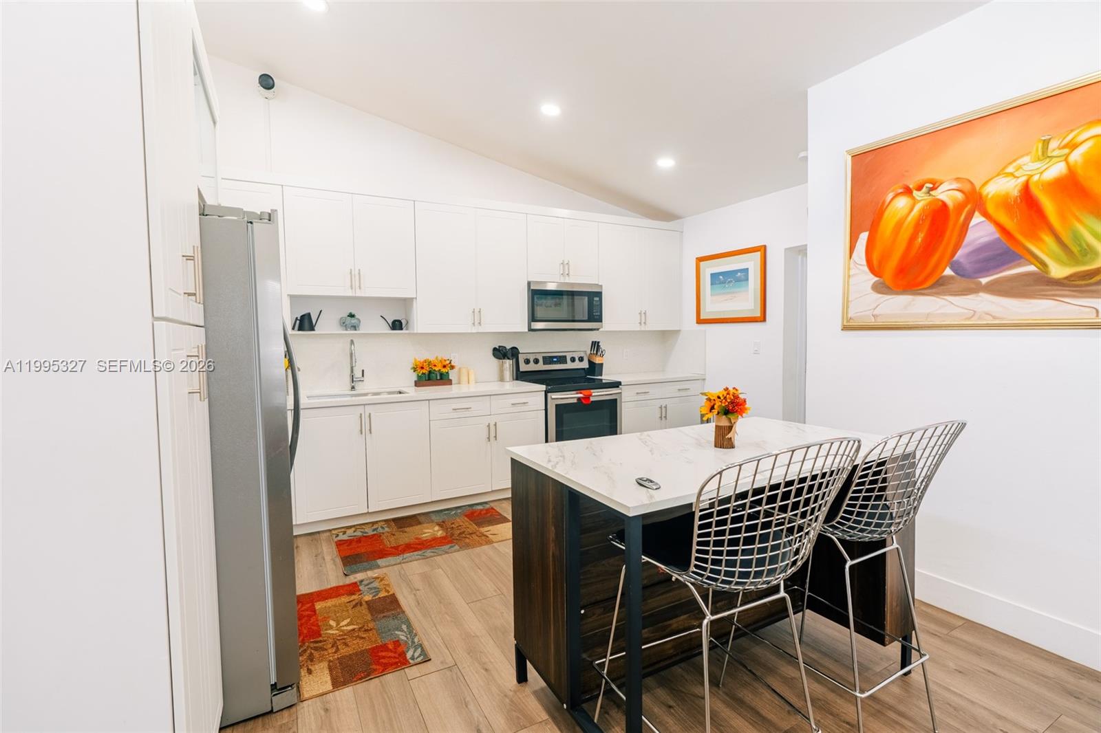 A modern kitchen features white cabinetry, stainless steel appliances, and a marble-topped kitchen island — 920 NW 84th St, Miami FL 33150, MIAMI, FL