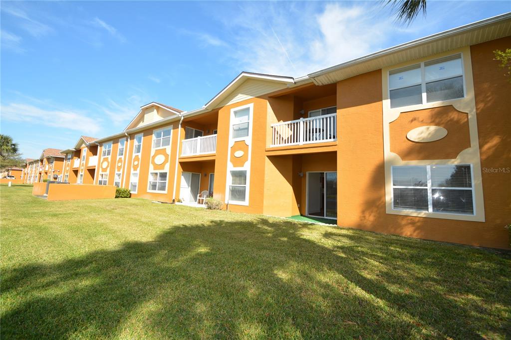 An exterior view of a multi-story apartment building with orange stucco walls and balconies — 4600 E MOODY BOULEVARD UNIT 4H, BUNNELL, FL