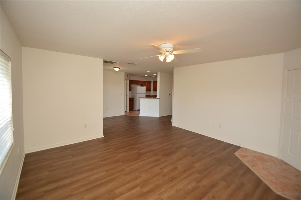 A living room with wood-look flooring leads to an open kitchen with white cabinets — 4600 E MOODY BOULEVARD UNIT 4H, BUNNELL, FL