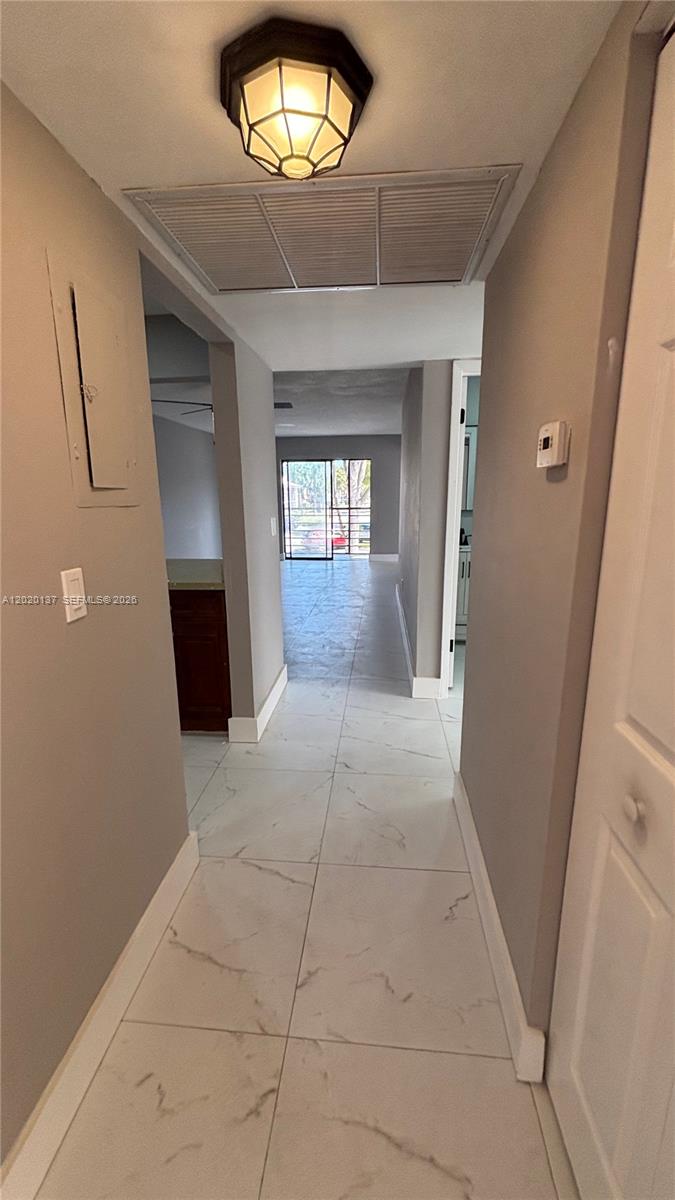 A hallway with white marble-style tile flooring leads toward a room with a sliding glass door — 20825 NE 8th Ct # 19, Miami FL 33179, MIAMI, FL