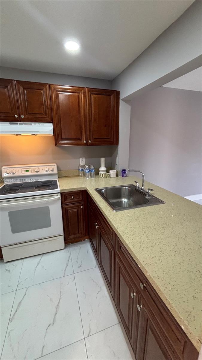 A kitchen features dark wood cabinets, a white stove, and a light-colored speckled countertop — 20825 NE 8th Ct # 19, Miami FL 33179, MIAMI, FL