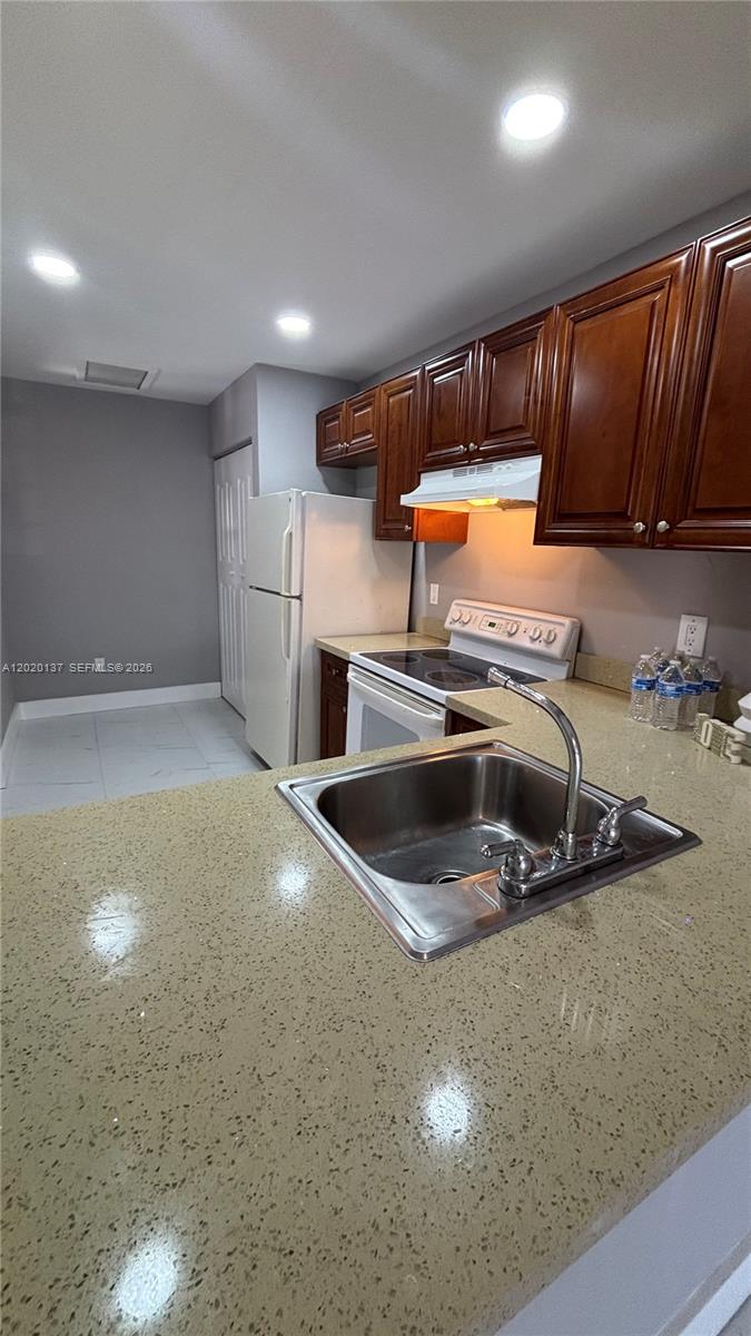 A kitchen features dark wood cabinets, a stainless steel sink, and a white refrigerator — 20825 NE 8th Ct # 19, Miami FL 33179, MIAMI, FL
