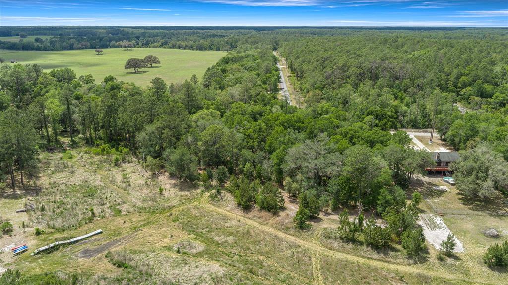 An aerial view shows a house with a pool surrounded by dense trees and open fields — TBD SW SHOREWOOD DRIVE, DUNNELLON, FL