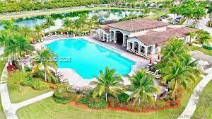 An aerial view shows a swimming pool next to a clubhouse building and a lake — 22911 SW 88th Pl # 21, Cutler Bay FL 33190, CUTLER BAY, FL