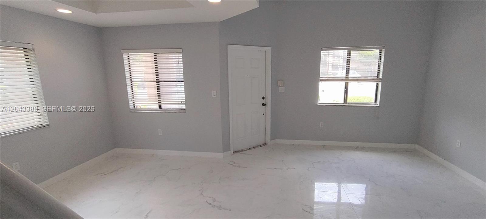 An empty room features light gray walls, white marble-style flooring, and three windows with blinds — 22911 SW 88th Pl # 21, Cutler Bay FL 33190, CUTLER BAY, FL