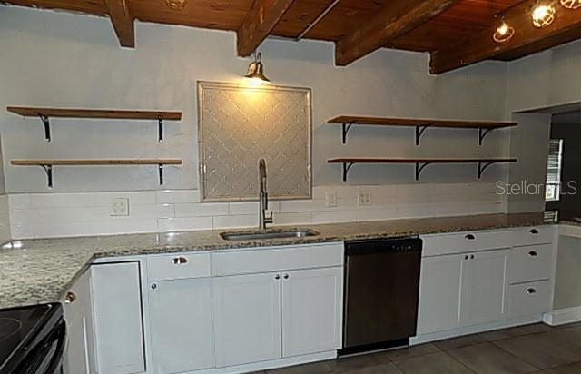 A kitchen features white cabinets, granite countertops, open wood shelving, and a stainless steel dishwasher — 2611 223RD STREET E, BRADENTON, FL