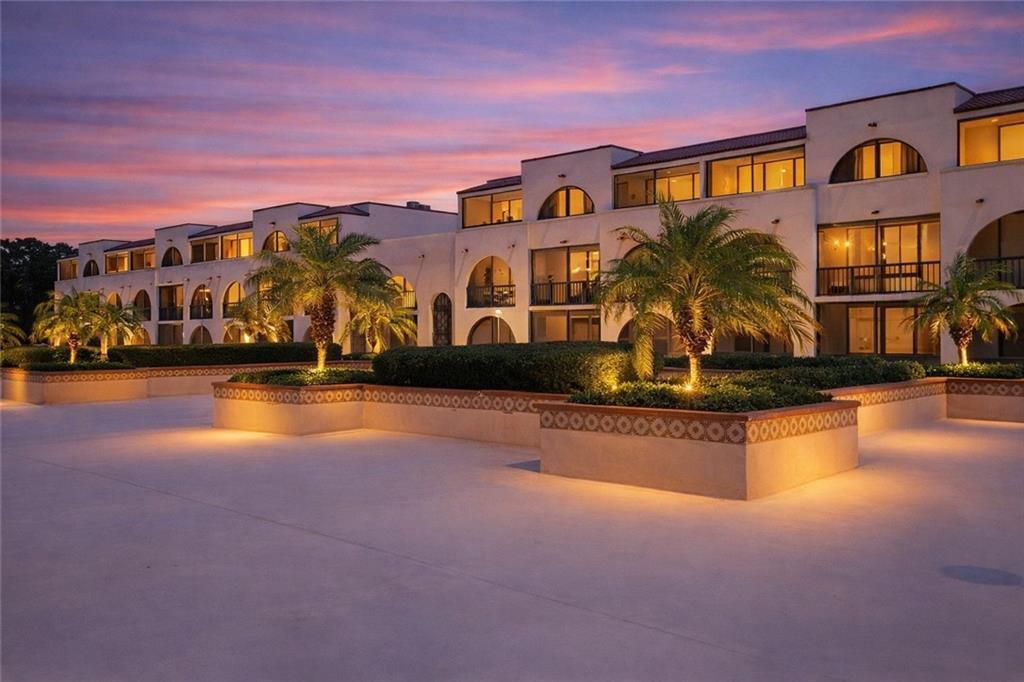 A multi-story white building with arched balconies and palm trees at sunset — 5601 Highway A1a # 304n, Vero Beach FL 32963, VERO BEACH, FL