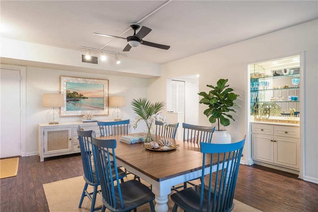 A dining room features a wooden table with blue chairs, a sideboard, and a bar — 5601 Highway A1a # 304n, Vero Beach FL 32963, VERO BEACH, FL