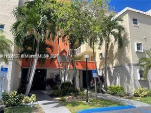 A multi-story apartment building with orange accents, palm trees, and a concrete walkway — 8255 Lake Dr # 204, Doral FL 33166, DORAL, FL