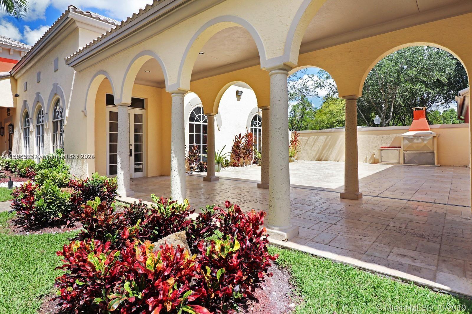 A covered patio with arched columns, tiled flooring, and an outdoor fireplace in a courtyard — 8255 Lake Dr # 204, Doral FL 33166, DORAL, FL