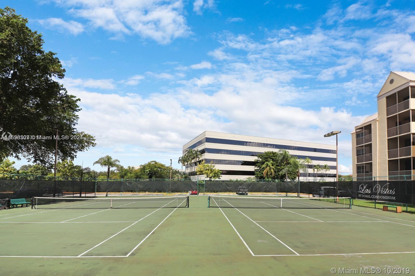 Two outdoor tennis courts are situated next to a large office building and apartment complex — 8255 Lake Dr # 204, Doral FL 33166, DORAL, FL