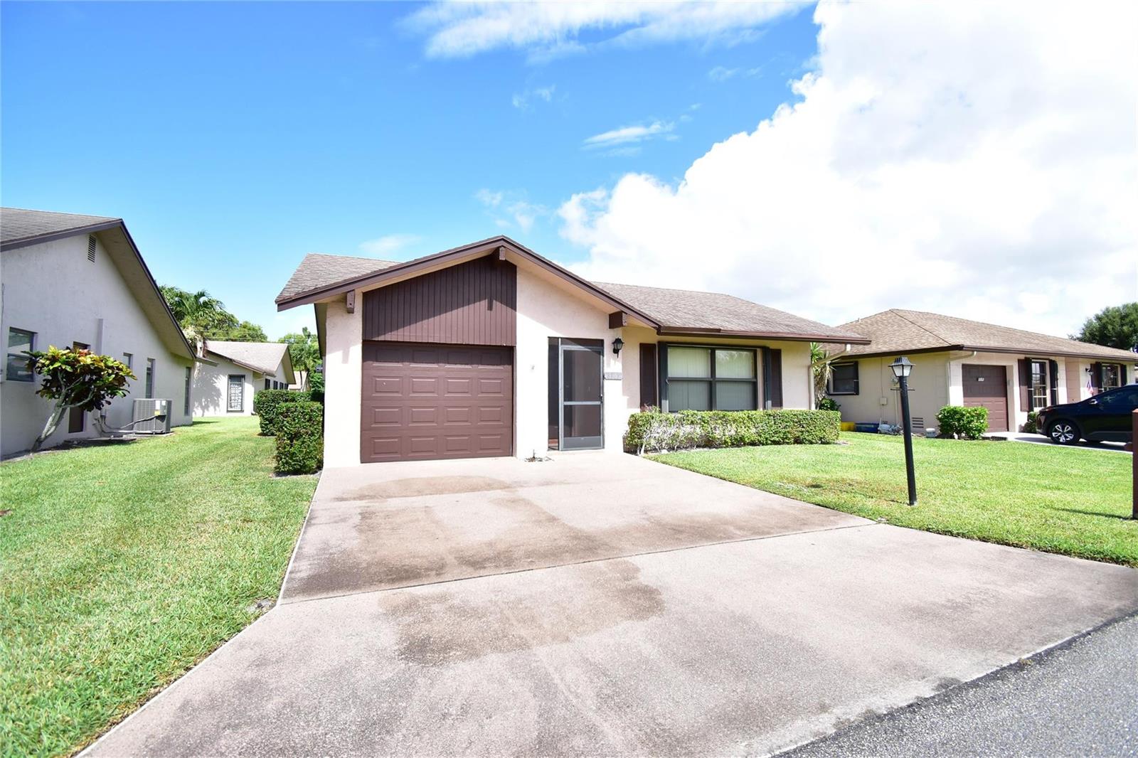 A single-story house with a brown garage door, a screen door, and a concrete driveway — 3305 Silver Buttonwood Drive, FL 33463, FL