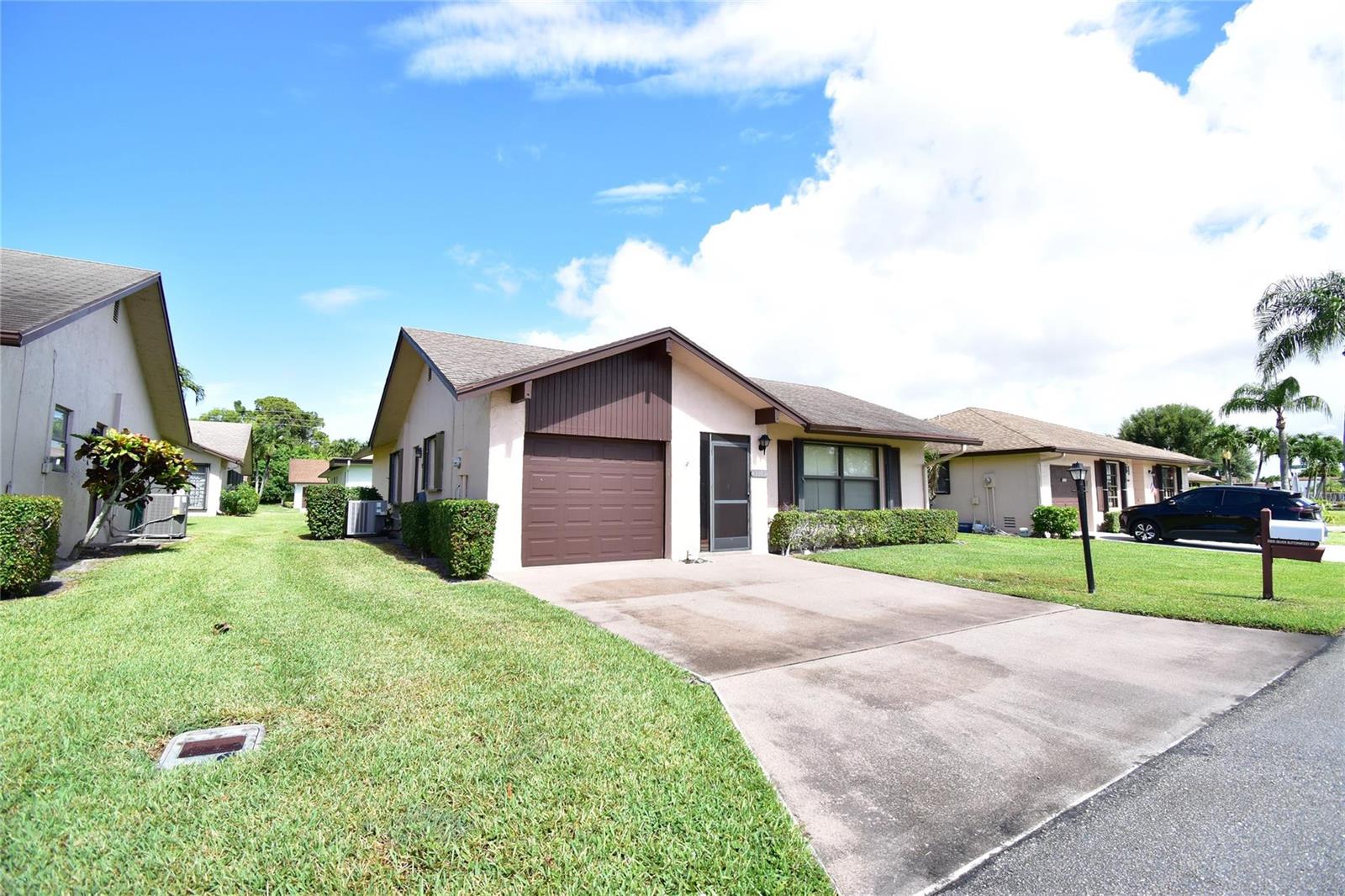 A single-story house with a brown garage door, a concrete driveway, and a grassy lawn — 3305 Silver Buttonwood Drive, FL 33463, FL