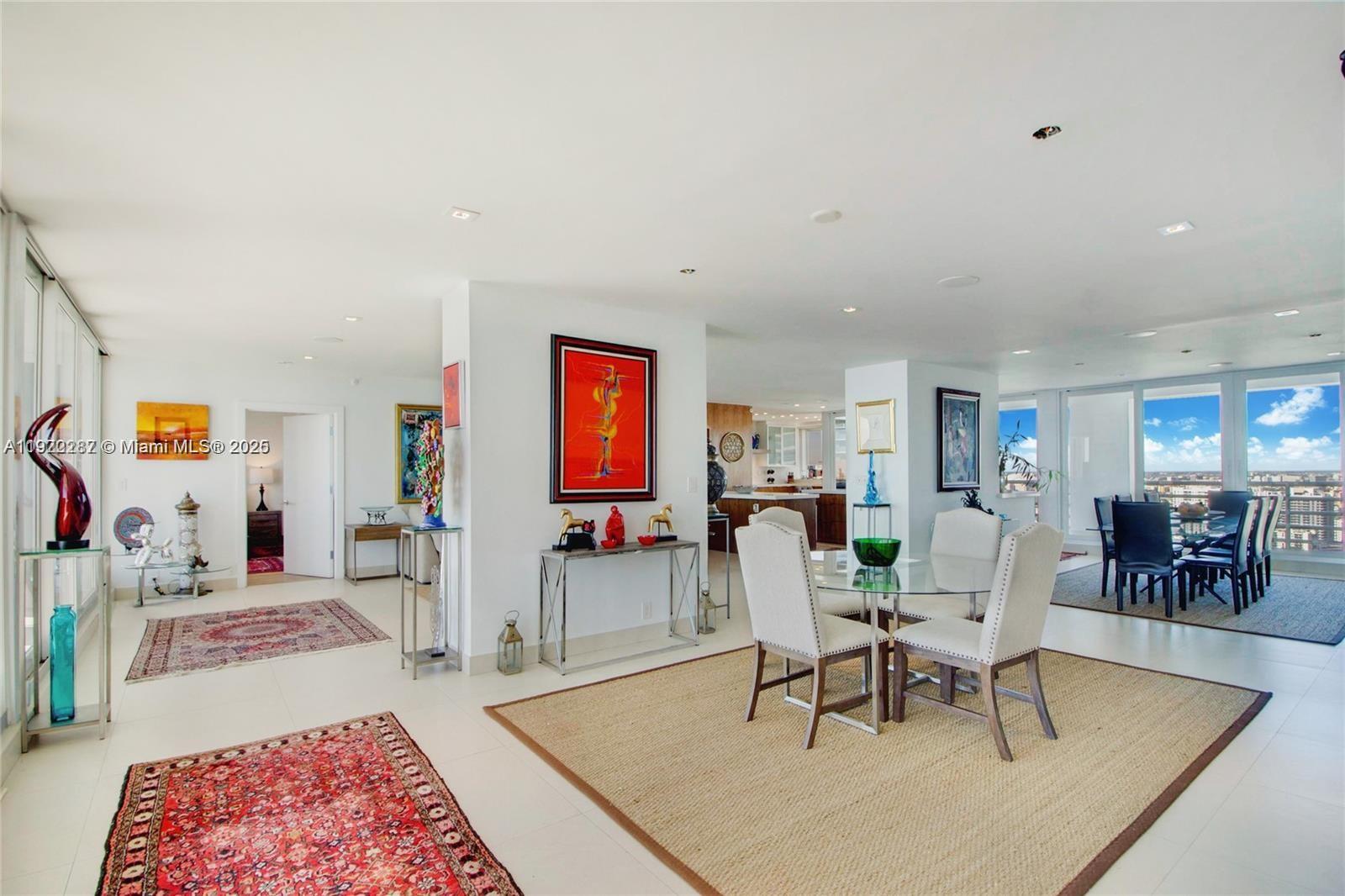 A bright, open-concept living and dining area features white tile floors and modern art — 1541 Brickell Ave # 3902, Miami FL 33129, MIAMI, FL