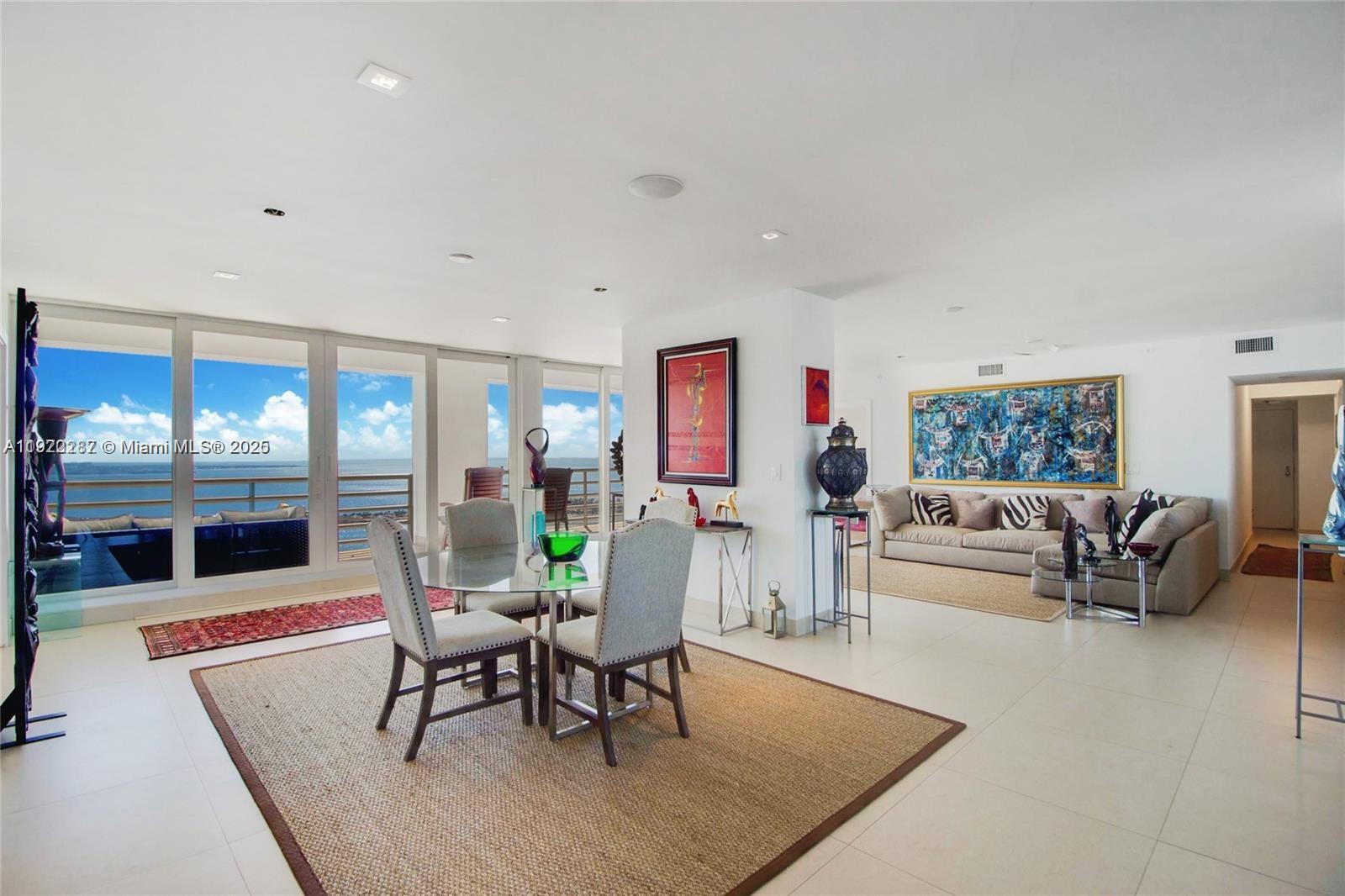 A bright, open-concept living and dining area features tile floors, a glass table, and ocean views — 1541 Brickell Ave # 3902, Miami FL 33129, MIAMI, FL