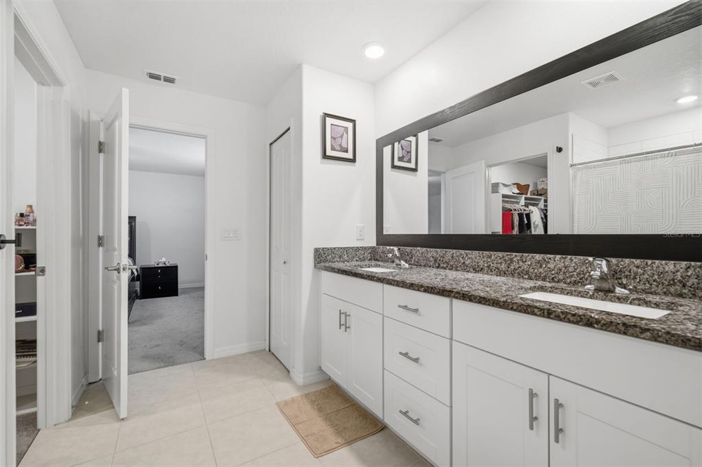A bathroom features a double vanity with granite countertops, white cabinets, and a large mirror — 6469 BAR S BAR TRAIL, ZEPHYRHILLS, FL