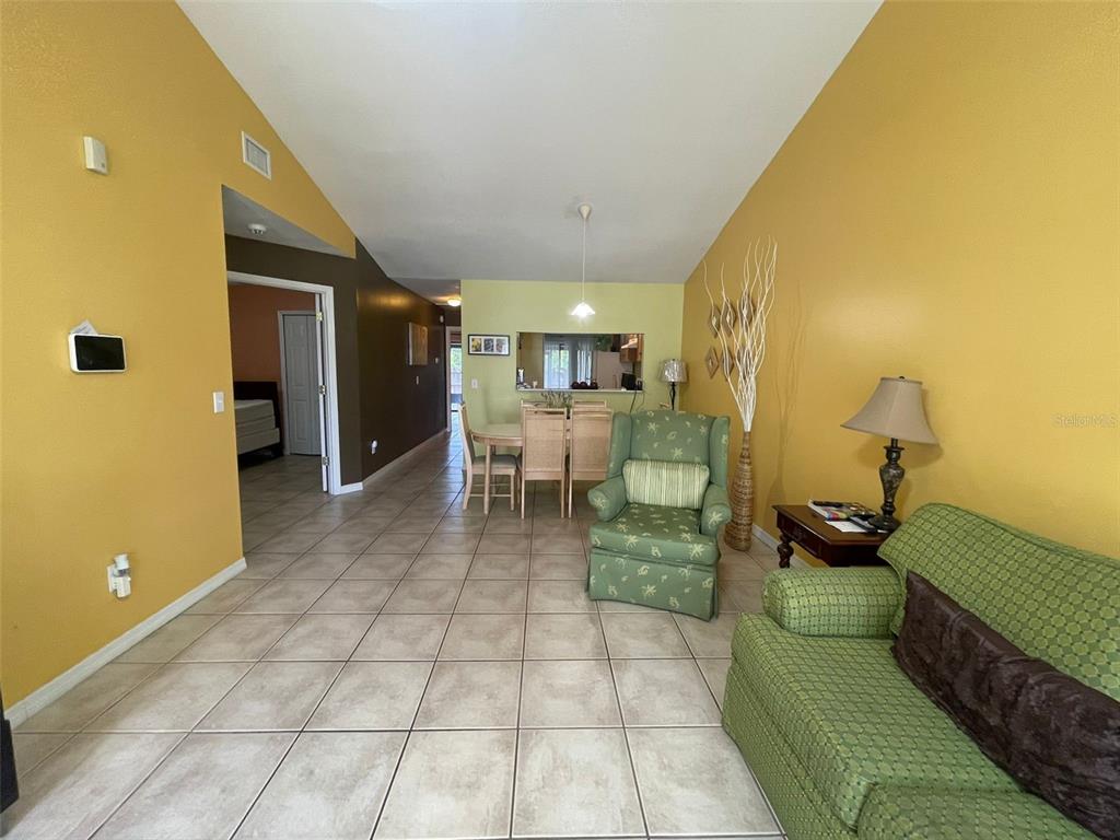 A living and dining area features yellow walls, tile flooring, and a vaulted ceiling — 3004 JON JON COURT, ORLANDO, FL