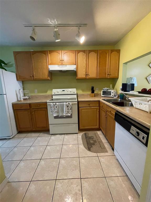 A kitchen features light wood cabinets, a white stove, and light-colored tile flooring — 3004 JON JON COURT, ORLANDO, FL