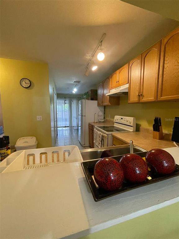 A kitchen features wood cabinets, a white stove, and a counter with decorative red spheres — 3004 JON JON COURT, ORLANDO, FL